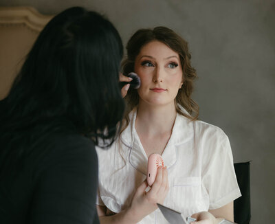 A bride getting her wedding makeup applied, representing full service wedding planning in Eugene by Birdie June Events and Rentals. 