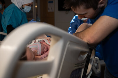 a peek-a-boo view through a hospital bed to see mother holding her newly born baby