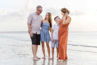 Family of four smiling at each other on the beach