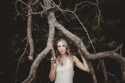 Caroline Weiss in a wooded setting, representing grounding energy and spiritual alignment.
