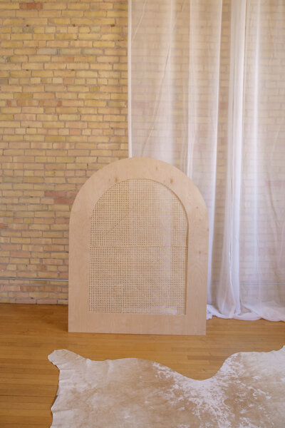 A five foot caned arch set up in front of a brick wall.