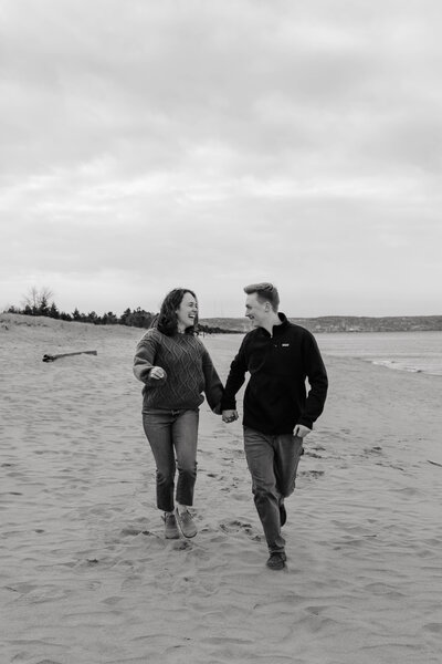 Bride and groom celebrating their engagement while walking down a beach