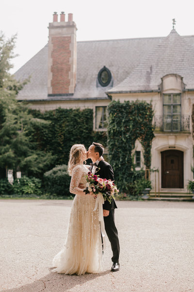 wedding couple kissing in front of mansion