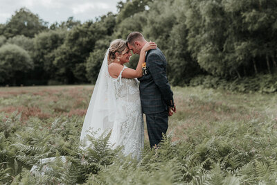 Bride & Groom standing forehand to forehand amongst fern on their wedding day Two Woods Estate, Pulborough