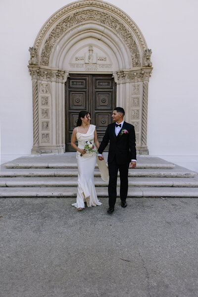 The bride and groom walking up down stairs holding hands.