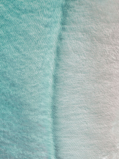 Aerial photo of soft blue ocean meeting white sand, symbolizing bespoke, detail-oriented social strategy