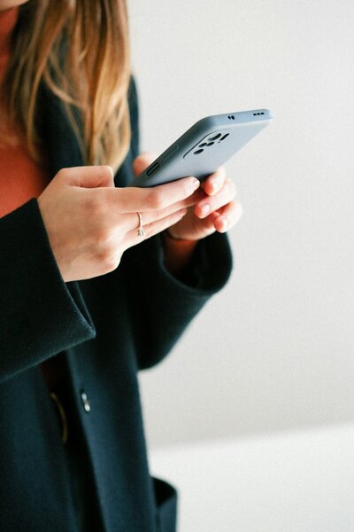 Girl holding a mobile phone, contacting Untamed Roots Creative.