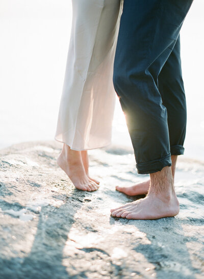 Shot of the couple's legs as they stand on a rock and kiss