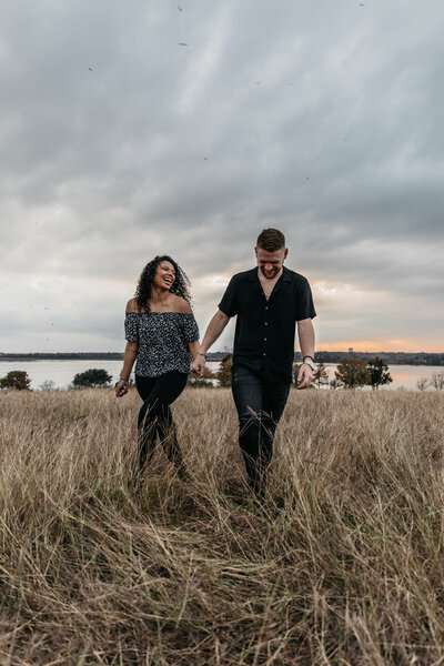 Couple walks hand in hand together in a grassy field for San Antonio, TX family and wedding photographer