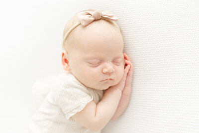 Closeup of sleeping baby girl wearing headband and smiling by Northern Virginia Newborn Photographer
