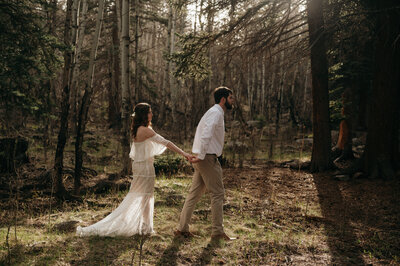 bride and groom walking through woods