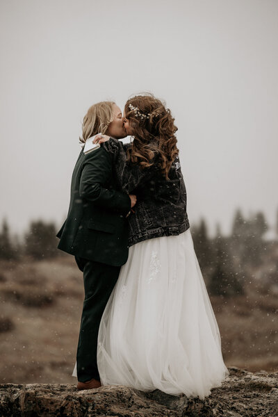 Brides share first kiss at LGBTQ mountain elopement.