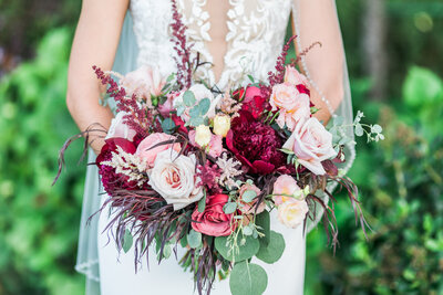 Bride holding bouquet with pink and burgundy flowers