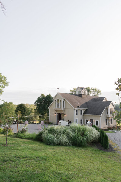 Outdoor summer evening shot of the historic barn at Willow Hill Event Venue in Brooklyn, Connecticut, illuminated against the sunset sky, showcasing its charm and rustic elegance.