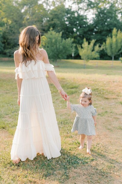 mom-and-daughter-holding-hands-walking-in-backlight