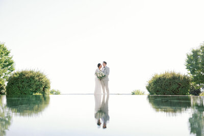 bride and groom reflected in a looking pond