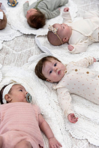 Group of babies laying in a circle on the floor