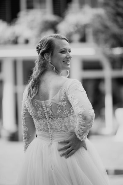 Bruid poseert elegant met arm in haar zij, stralend op haar trouwdag, perfect gepland door een weddingplanner en ceremoniemeester