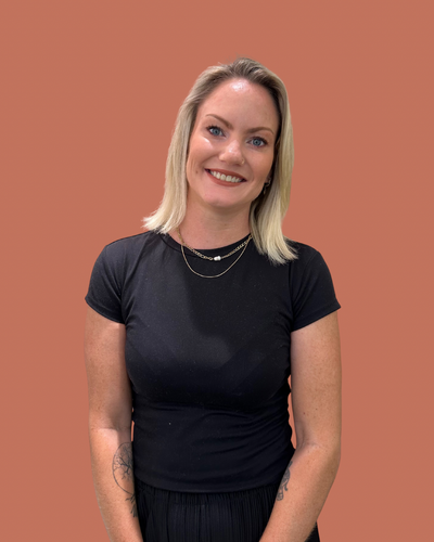 Kelsey, Female Senior hairstylist with balayage hair, dressed in a black tee.