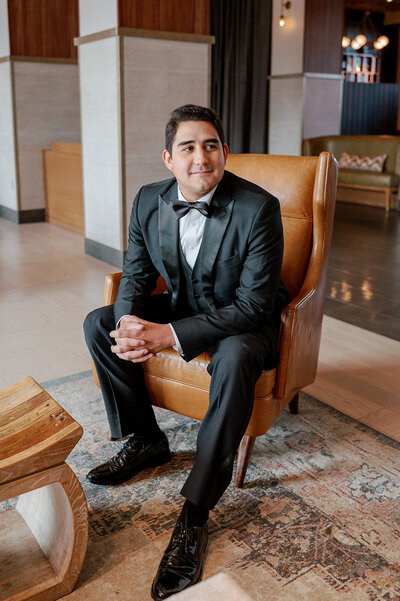 groom sitting on a leather chair before ceremony