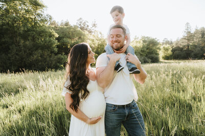 mom and dad holding son walking in the field