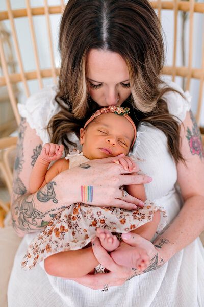 Mother cradling her newborn baby in a cozy indoor setting captured by Jennifer L. Kirk Photography in Allen, Texas. Newborn photographer preserving tender moments of motherhood and connection.