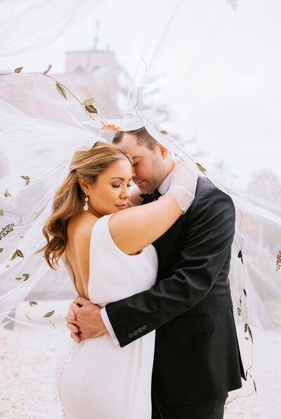 man and woman embracing underneath bridal veil