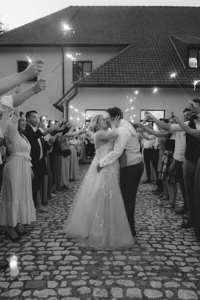 Bruidspaar staat voor glazen serre en drinkt champagne.