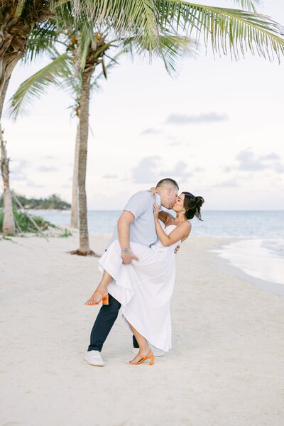 Newlywed couple barefoot on a beachfront deck, sharing a joyful dance surrounded by tropical views.