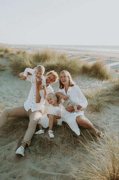Koppel zit in de duinen met hun drie kinderen