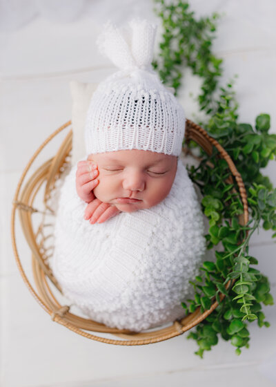Baby girl, sitting in brown bowl wearing white dress during photoshoot with Nashville, TN photographer 