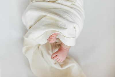 Portland Newborn Photographer_ close up photo of newborn baby toes wrapped with a light yellow swaddle