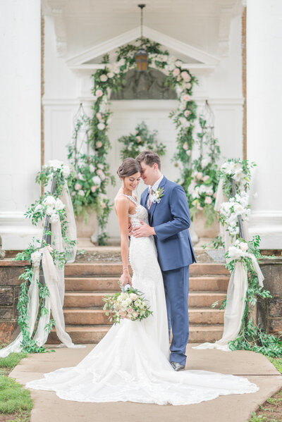 Bride and groom standing together surrounded by florals by an entrance