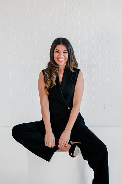 Cardiologist wearing black pantsuit smiling naturally in modern San Antonio studio branding photo.