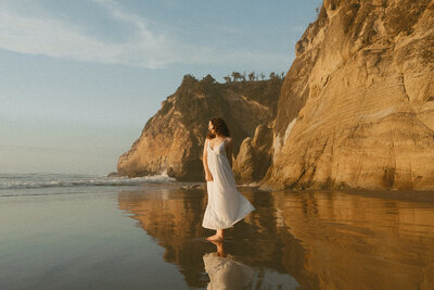 girl in green dress standing on oregon coast beach