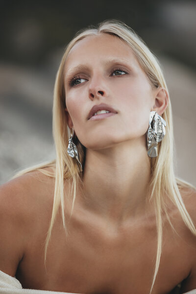Close-up van model Johanna met zilveren statement oorbellen, gefotografeerd bij zonsopgang in Kaapstad.