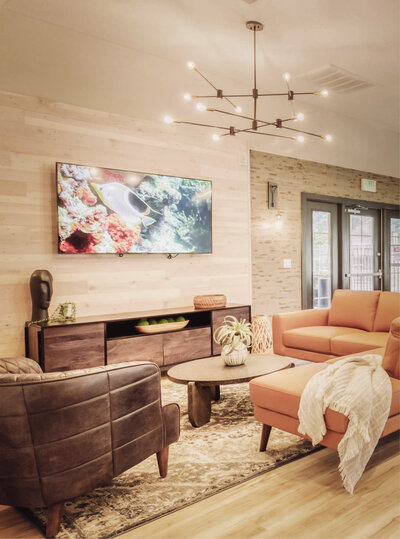 Inviting lounge at Villas at Scenic River featuring warm tones, leather seating, modern lighting, and a mounted TV.