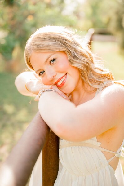 Senior girl leaning on fence post posing for senior photo