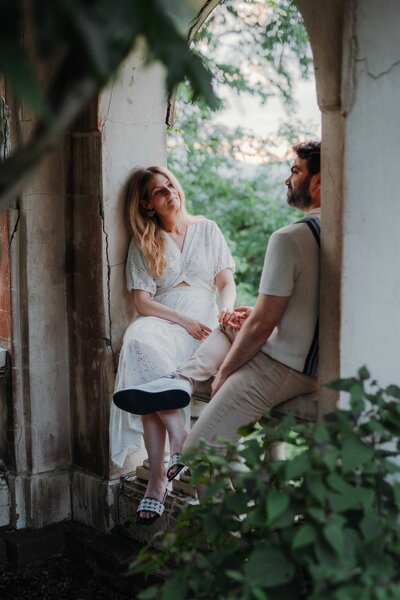 An engaged couple sitting in an archway at Bard College's Blithewood Garden in upstate NY