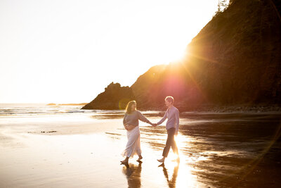 Couple walking on the beach at sunset during a Portland maternity photographer session. 