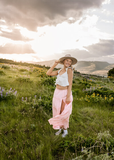 Girl taking senior portraits in a field of wildflowers