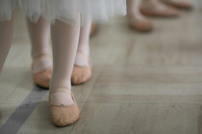 Close-up of children's feet in soft ballet shoes and tutus, symbolizing innocence, grace, and the hope of new beginnings through adoption.