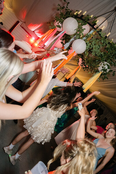 Candid reception moment with wedding guests dancing under string lights documented by wedding photographer Austin TX, Erin Marcin