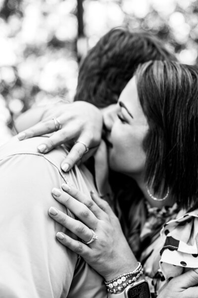 Black and white photo of newly engaged couple, hugging and  smiling with happy tears and ring