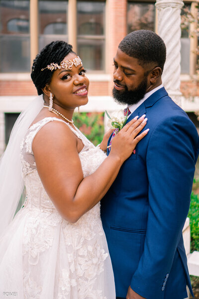 Bride resting her hands on the grooms chest under an arch. 