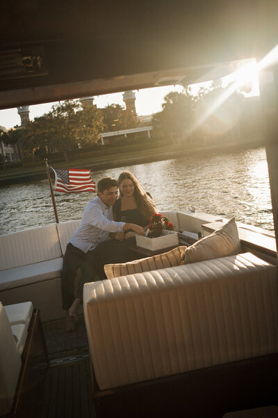 couple eating charcuterie snacks celebrating their engagement on a boat at sunset