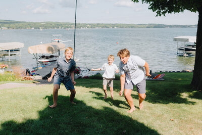 Kids playing together on a grassy verge overlooking a lake