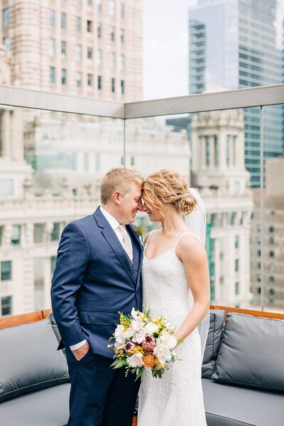 Bride and groom smile with their foreheads together on a rooftop in Chicago