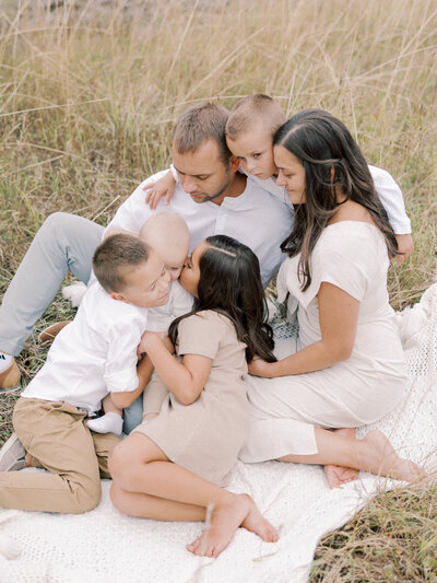 Man and woman sitting in field with four young children