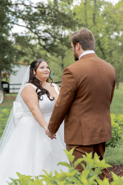 Husband and wife exchanging private vows after their first look, in a private outdoor setting near Hickory, NC. Husband is wearing a burnt orange suit and facing his wife, wearing a beautiful white dress.